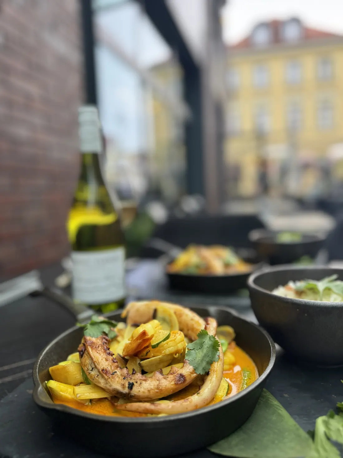 Yellow curry z owocami morza z grillowanymi mackami kałamarnicy, białe wino, w tle kamienice przy Starym Rynku – King Fu Fusion Bydgoszcz