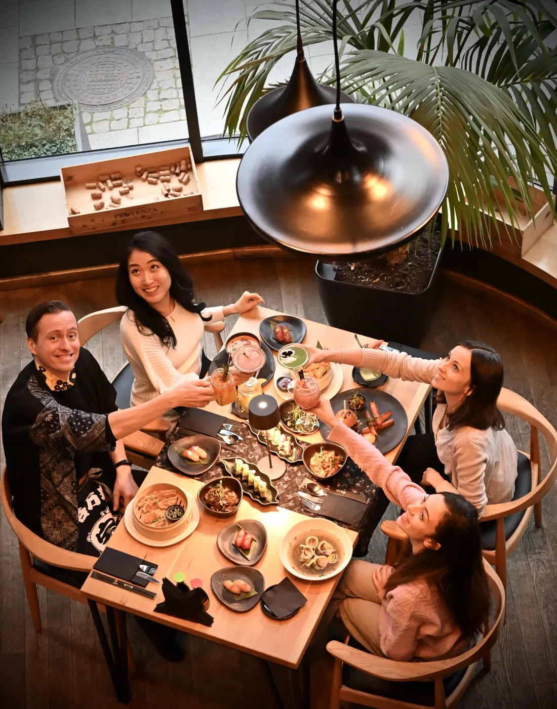 Przyjaciele wznoszą toast koktajlami przy stole pełnym dań – sushi, nigiri, gyoza, tataki i zupa z małżami – widok z góry, King Fu Fusion Bydgoszcz