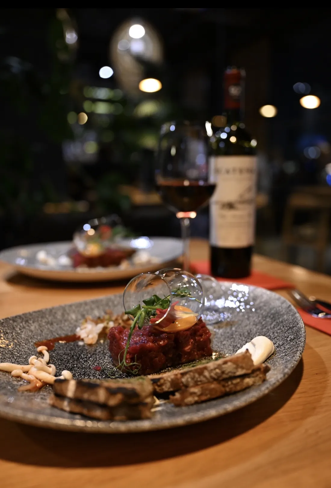 Tatar z polędwicy wołowej z grzankami i czerwonym winem przy stoliku wieczorem – King Fu Fusion Bydgoszcz