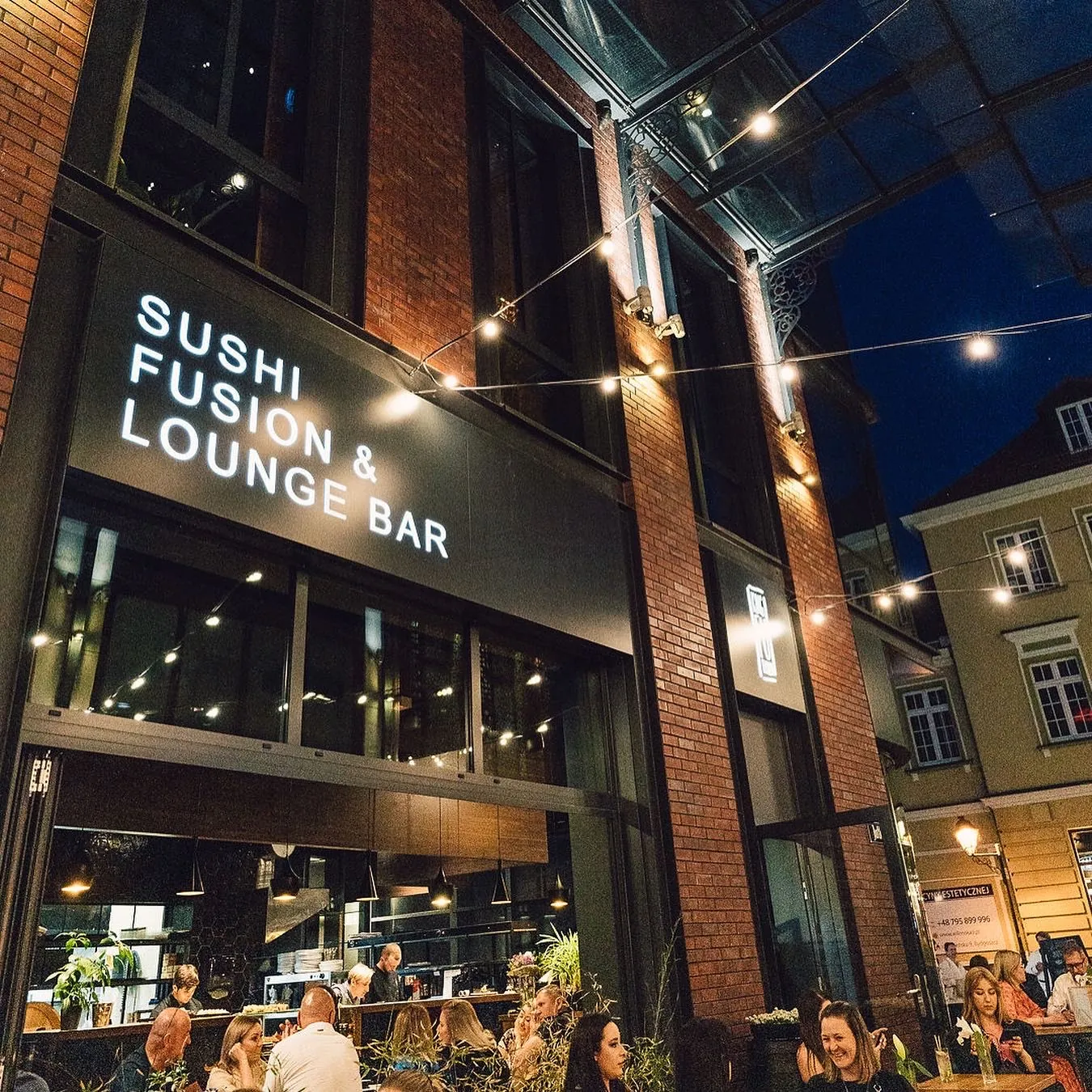 Ogródek restauracji King Fu Fusion wieczorem – szyld Sushi Fusion & Lounge Bar i goście przy stolikach, Jatki, Bydgoszcz