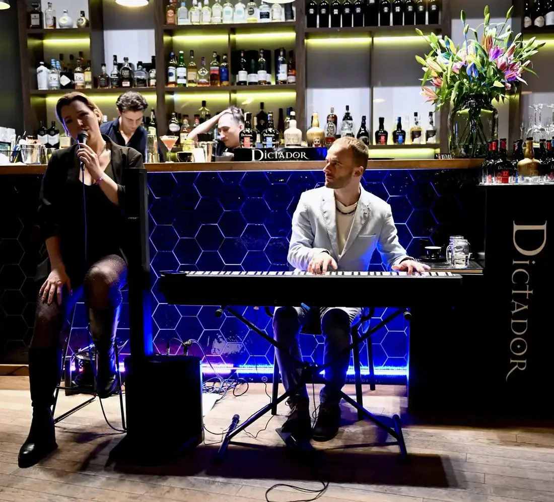 Adela – wokalistka – i pianista grają na żywo przy podświetlonym lounge barze King Fu Fusion, za barem barmani przygotowują koktajle – Bydgoszcz