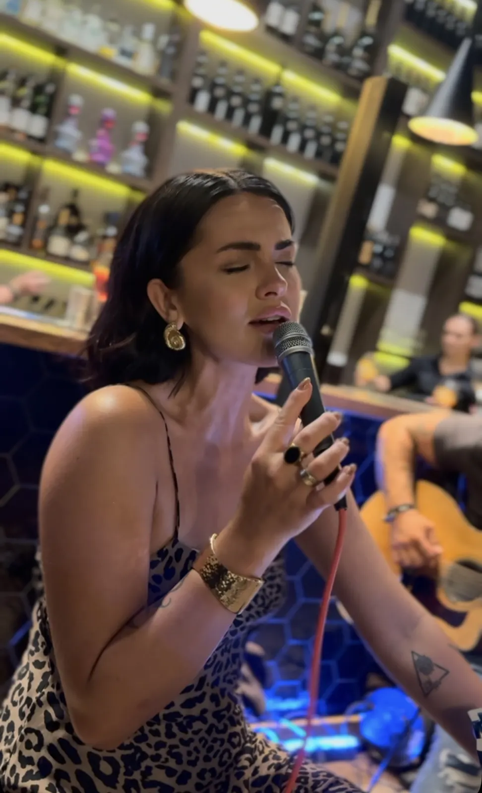 Ania Hnatowicz śpiewa na żywo przy podświetlonym barze King Fu Fusion, w tle gitarzysta Marcin Cholewa – Bydgoszcz