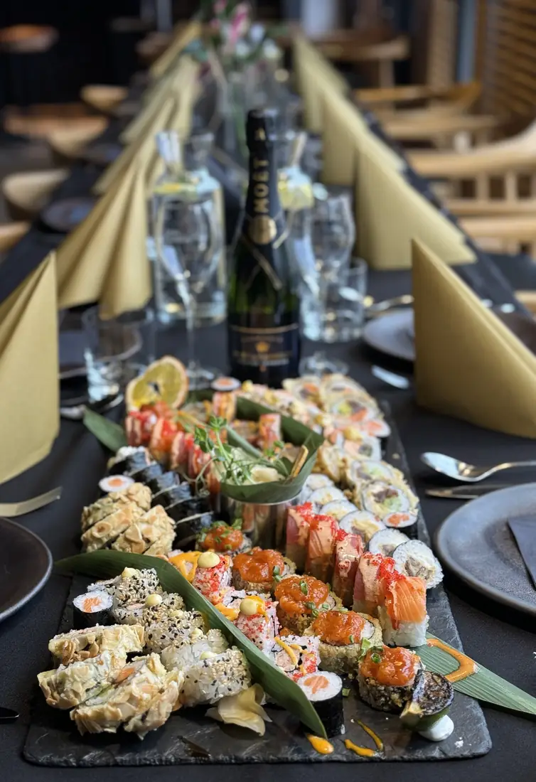 Długi stół bankietowy ze złotymi serwetkami, duży półmisek sushi i szampan Moët – przyjęcie w King Fu Fusion Bydgoszcz