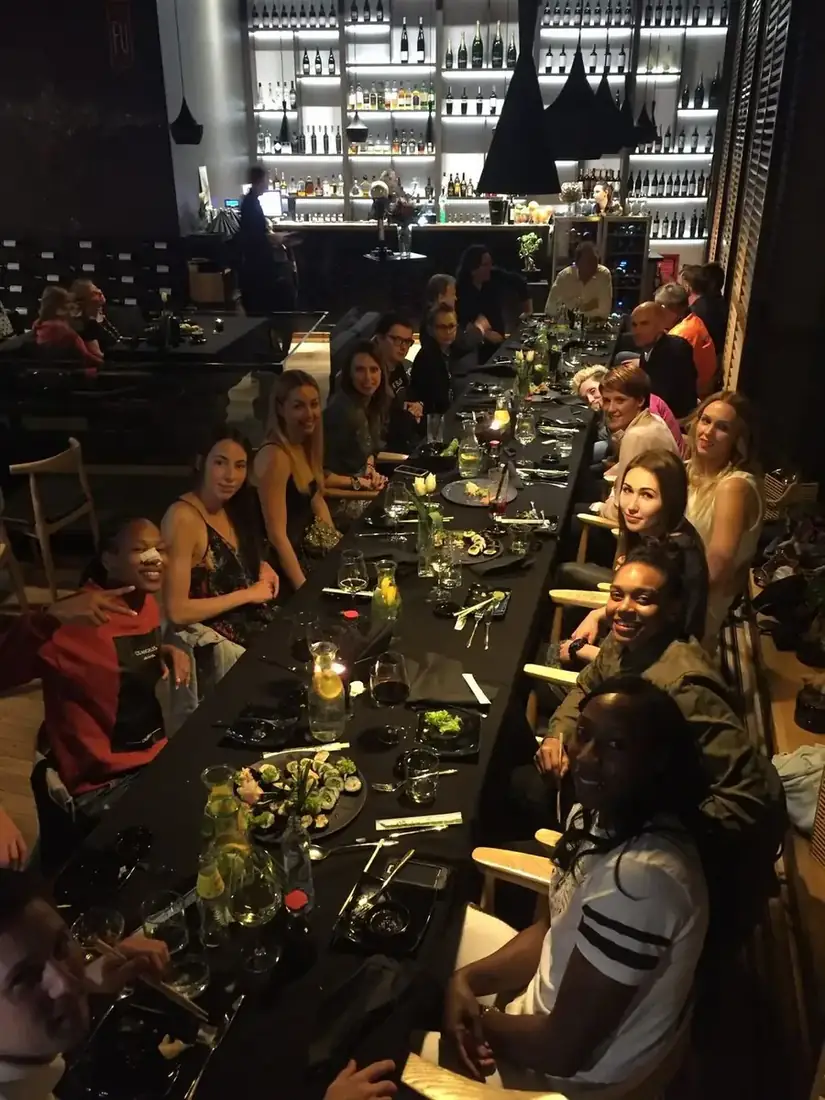 Duża grupa gości przy długim stole z sushi, winem i karafkami wody z cytryną, w tle podświetlony bar – kolacja grupowa w King Fu Fusion Bydgoszcz