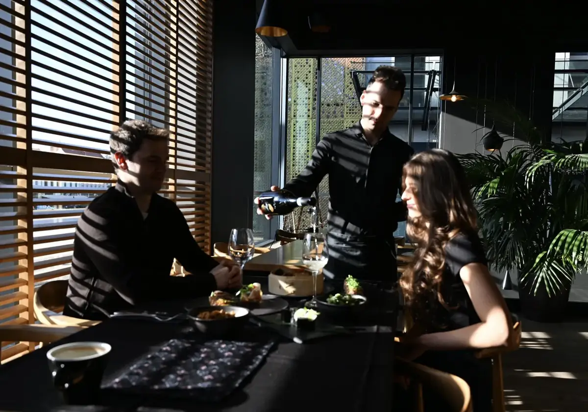 Kelner Fryderyk nalewa wino parze przy stoliku przy oknie z drewnianymi okiennicami – kolacja w restauracji King Fu Fusion w Bydgoszczy
