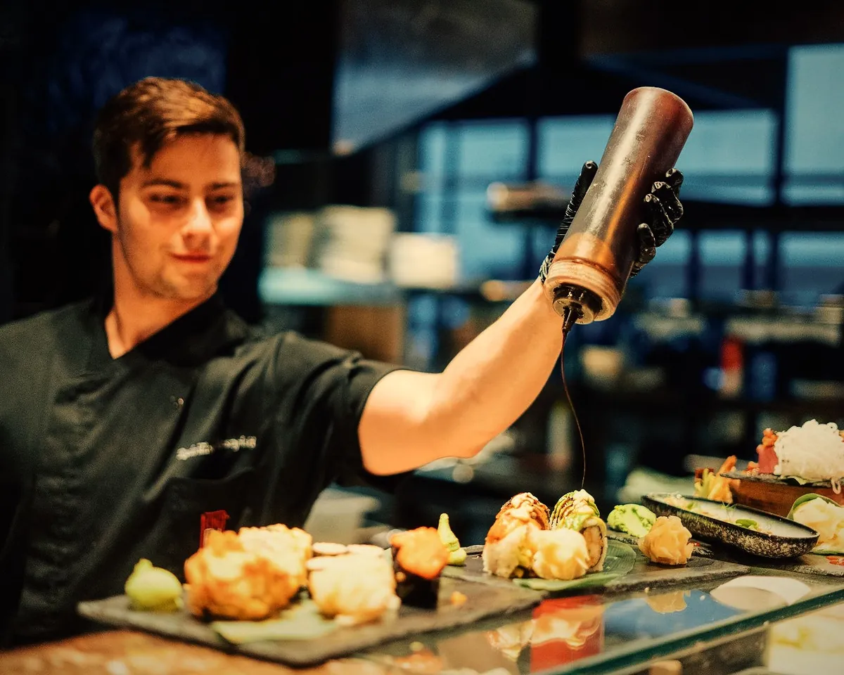 Kucharz sushi polewa sosem rolki na łupkach przy barze sushi – King Fu Fusion Bydgoszcz