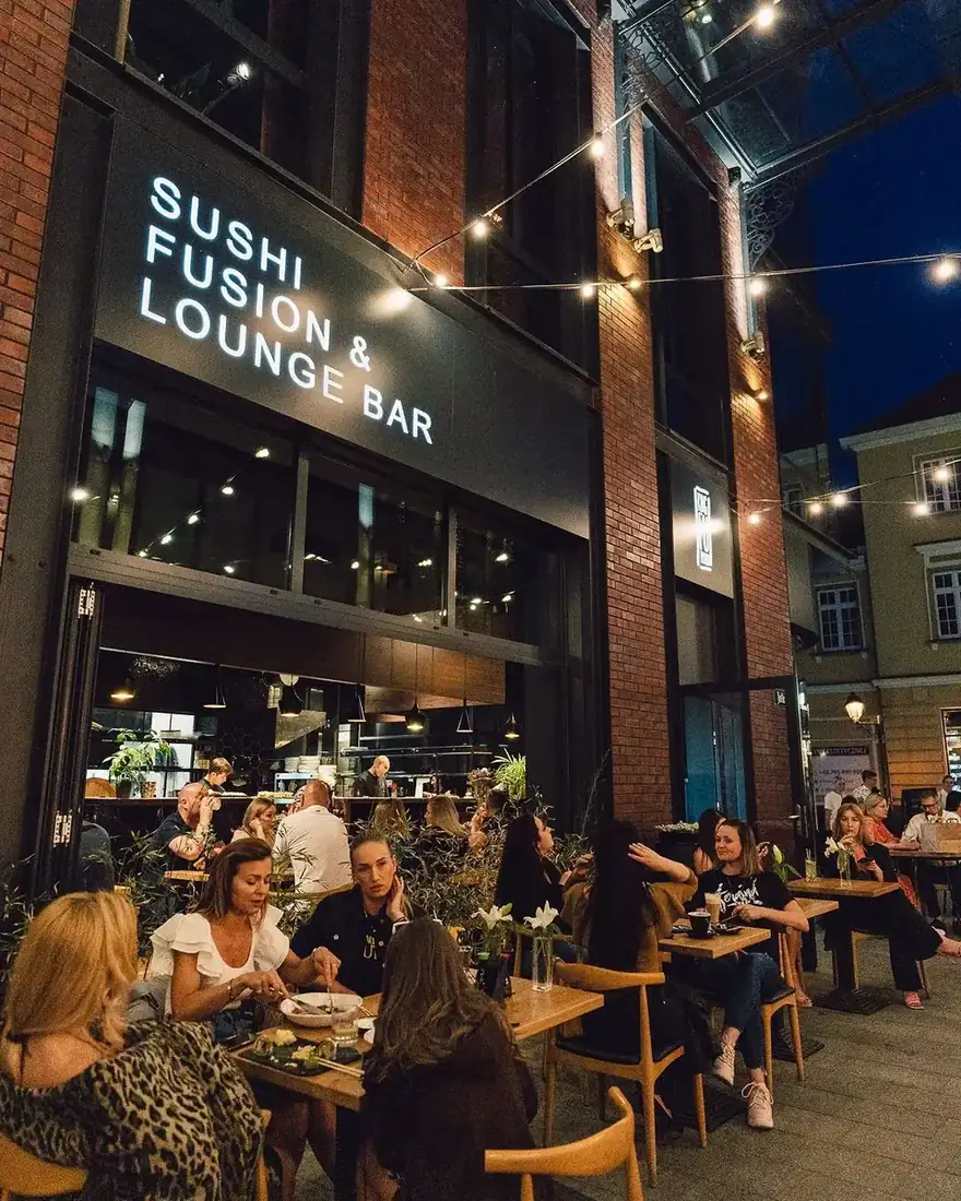 Ogródek restauracji King Fu Fusion przy ul. Jatki 2 w Bydgoszczy wieczorem – goście przy stolikach pod girlandą świateł i podświetlony szyld Sushi Fusion & Lounge Bar