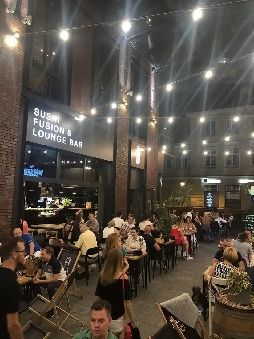 Pełen ogródek restauracji King Fu Fusion wieczorem pod girlandami żarówek – szyld Sushi Fusion & Lounge Bar, pasaż Jatki w Bydgoszczy