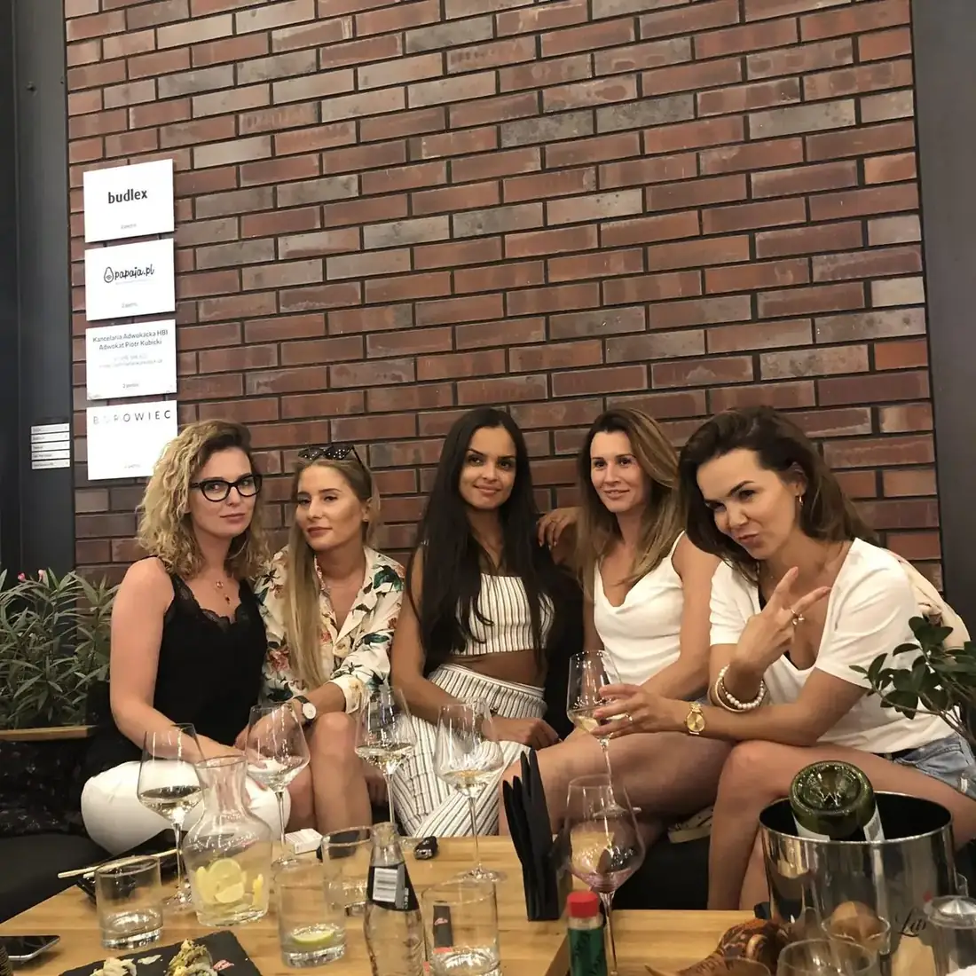 Pięć przyjaciółek przy stoliku z białym winem i sushi na tle ceglanej ściany w pasażu Jatki – King Fu Fusion Bydgoszcz