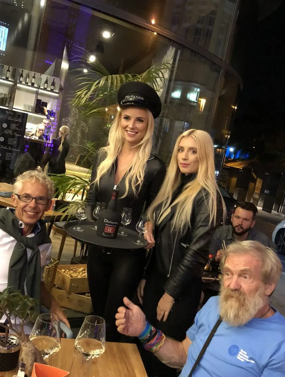 Podróżnik Franciszek Doba z gośćmi i hostessami z rumem Dictador 12 przy stoliku w ogródku King Fu Fusion wieczorem – Bydgoszcz