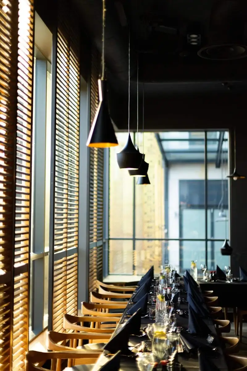 Sala restauracji King Fu Fusion w Bydgoszczy – nakryty stół przy oknach z drewnianymi okiennicami i czarnymi lampami