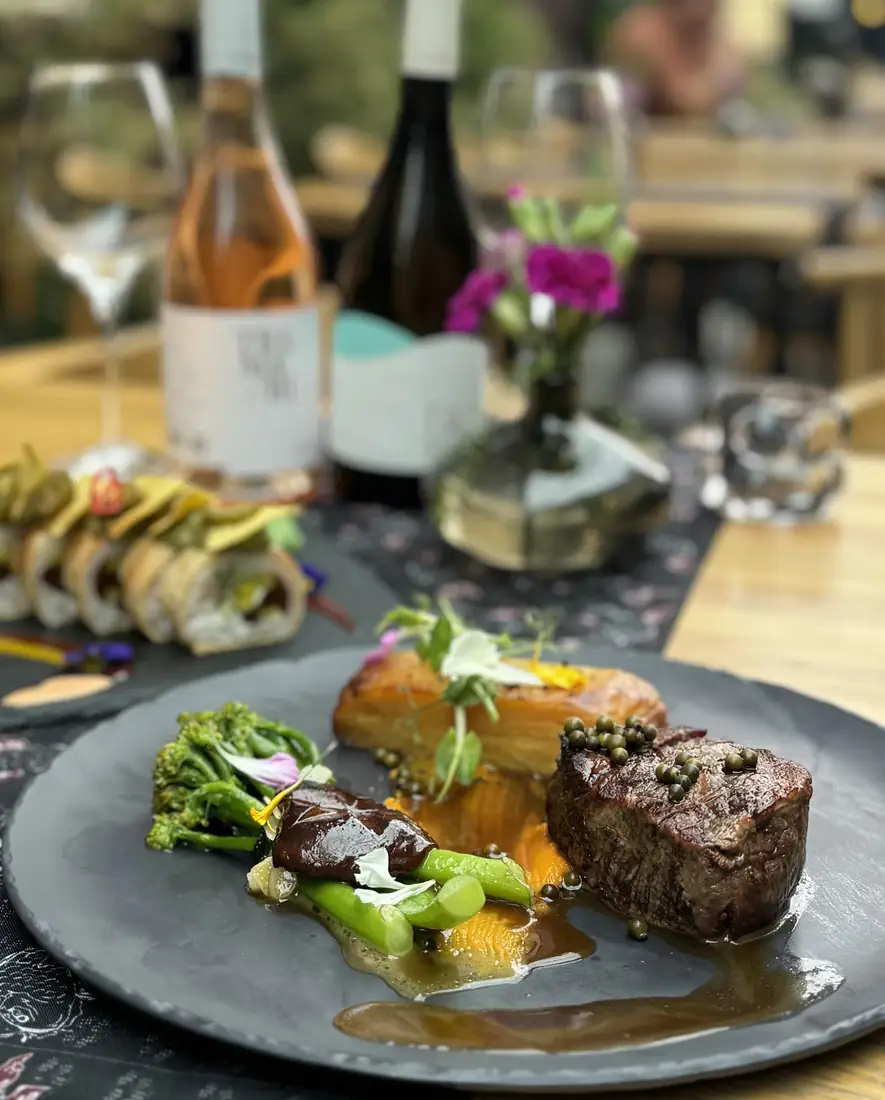Stek z polędwicy z zielonym pieprzem, shiitake, brokułem i zapiekanką ziemniaczaną, w tle wino różowe i białe – King Fu Fusion Bydgoszcz
