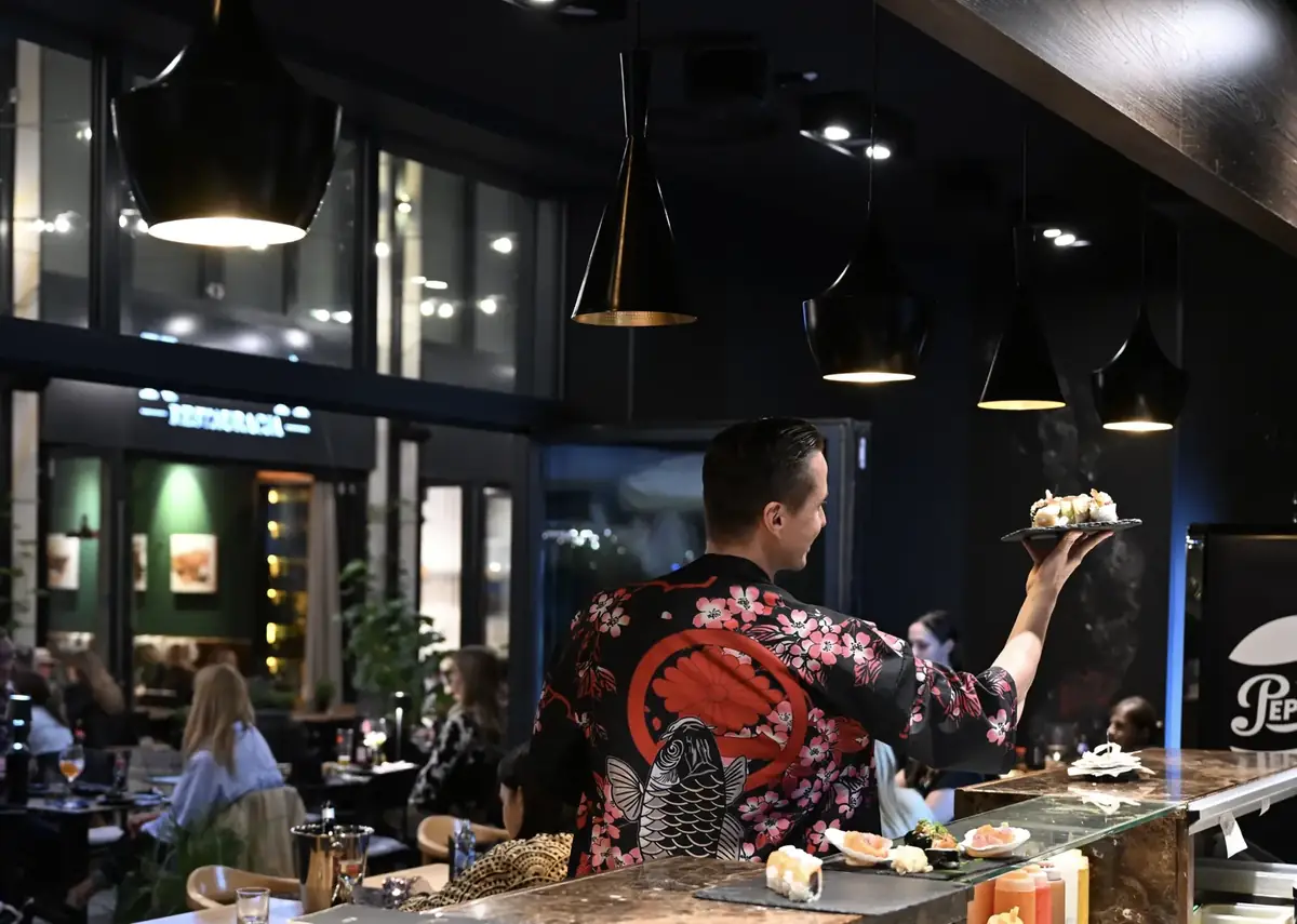 Sushi master w czarnym kimonie z karpiem koi i kwiatami wiśni wydaje rolki sushi na sali King Fu Fusion – Bydgoszcz
