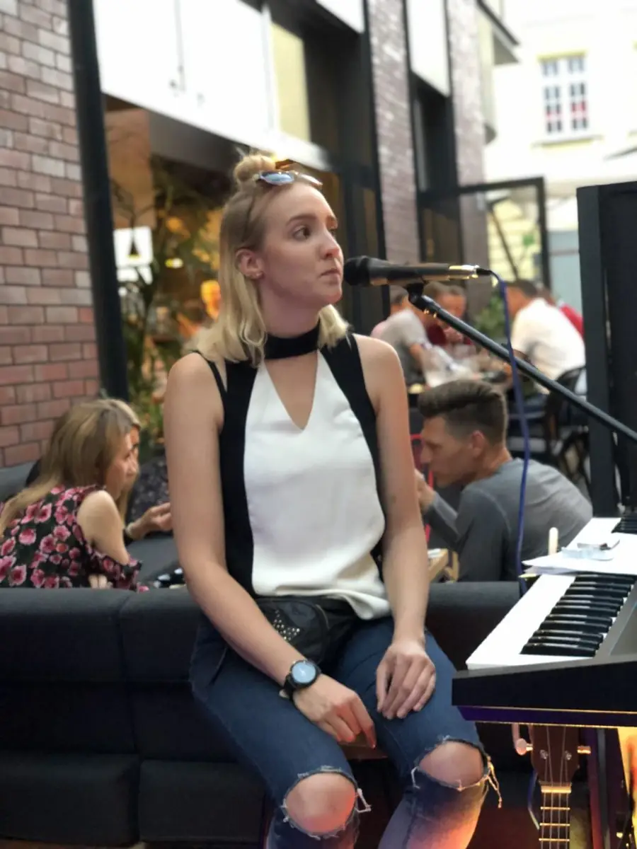 Wokalistka przy keyboardzie i mikrofonie podczas muzyki na żywo w ogródku King Fu Fusion, w tle goście przy stolikach – Jatki, Bydgoszcz